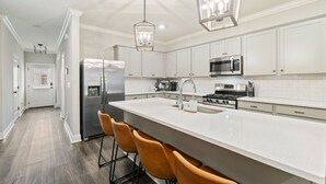 A modern kitchen with white cabinets, a large island, and bar stools.