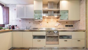 A modern kitchen with a stainless steel range hood, double oven, and a large sink. - Domu Arké by Propertize - above the ruins (Cagliari)