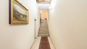 A hallway with a staircase, a framed painting on the wall, and a patterned carpet. - Domu Arké by Propertize - above the ruins (Cagliari)