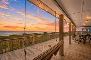 A wooden deck with a view of the beach and ocean at sunset. - Pet-Friendly | Beachfront | Sleeps 7 | Large Deck (Crystal Beach)