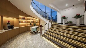 Ein modernes Interieur mit einer gewölbten Bücherwand, einer Treppe mit Glasgeländern und einem Essbereich.