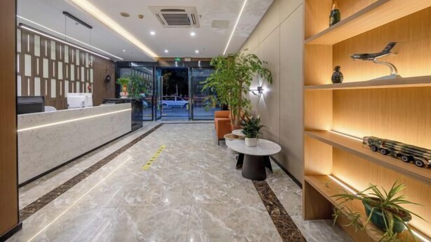 Eine moderne Hotellobby mit Empfangstresen, Marmorböden und Holzregalen mit Dekoration.