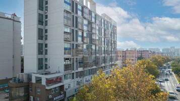 A multi-story building with balconies, a parking lot, and a tree in the foreground.