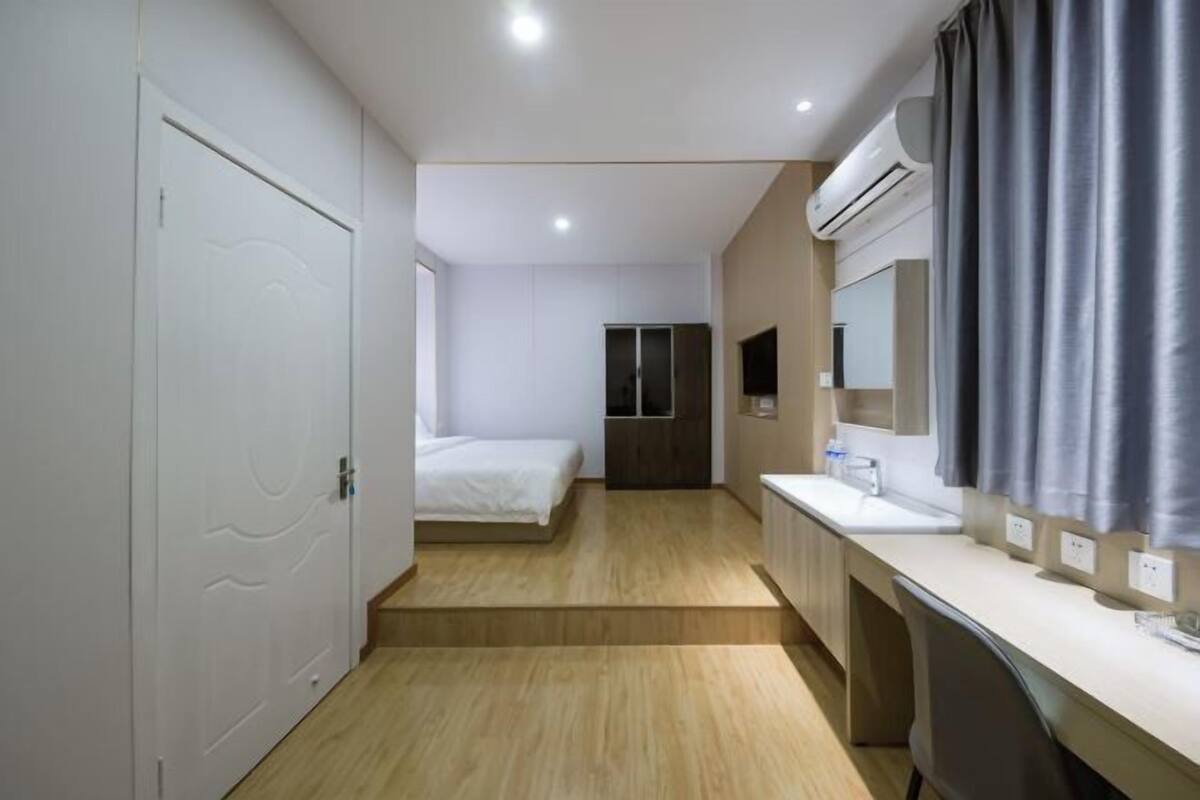 Une chambre d’hôtel avec un lit, un bureau, un miroir et une fenêtre.