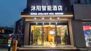 Das Moyang Intelligent Hotel mit moderner Fassade, großem Glas Eingang und einem Schild über den Türen.
