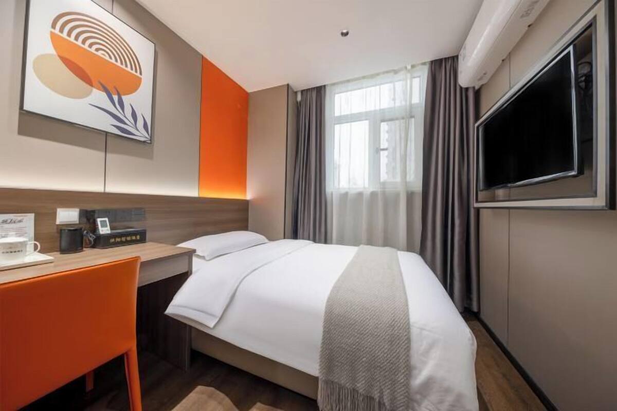 Une chambre d’hôtel avec un lit, un bureau, une télévision et une grande fenêtre.