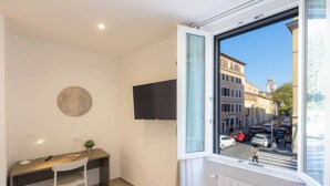 Una habitación moderna con escritorio, silla y un amplio ventanal con vista a la calle.