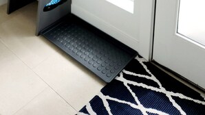 Un porte-chaussures contenant différentes paires de chaussures et une porte sur laquelle figure un texte indiquant la procédure à suivre pour effectuer le départ.
