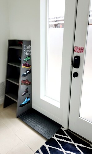 Een schoenenrek met verschillende paar schoenen en een deur met een tekstinstructie voor uitchecken.