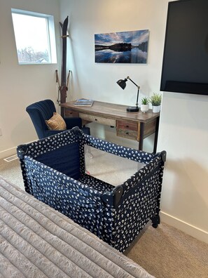 Een kamer met een houten bureau, een stoel, een bed met een stoffen hemel en een televisie aan de muur.