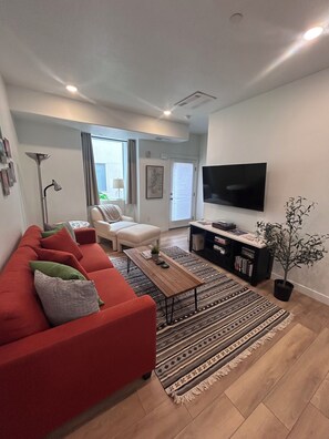 Ein modernes Wohnzimmer mit einem roten Sofa, einem Couchtisch, einem Fernseher und einem Bücherregal.