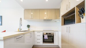Een moderne keuken met witte kasten, een inbouwoven en een aanrecht.