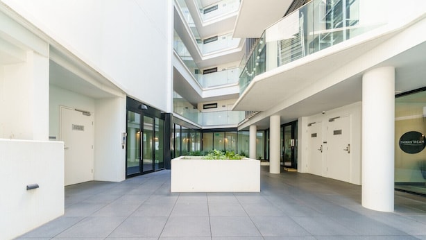 Een modern interieur met een centrale plantenbak, glazen wanden en een strakke, betegelde vloer.