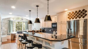 A modern kitchen with a large island, stainless steel appliances, and pendant lighting.