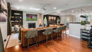 A modern kitchen with a bar area, wooden flooring, and a stone accent wall.