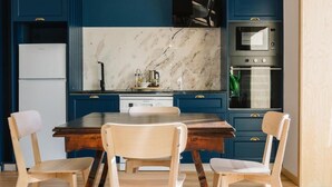 A kitchen with dark blue cabinets, a marble backsplash, and a wooden dining table with chairs. - Campanha Apartment by Porto Stories (Porto)