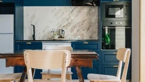 A modern kitchen with blue cabinets, a marble countertop, and a wooden dining table with chairs. - Campanha Apartment by Porto Stories (Porto)