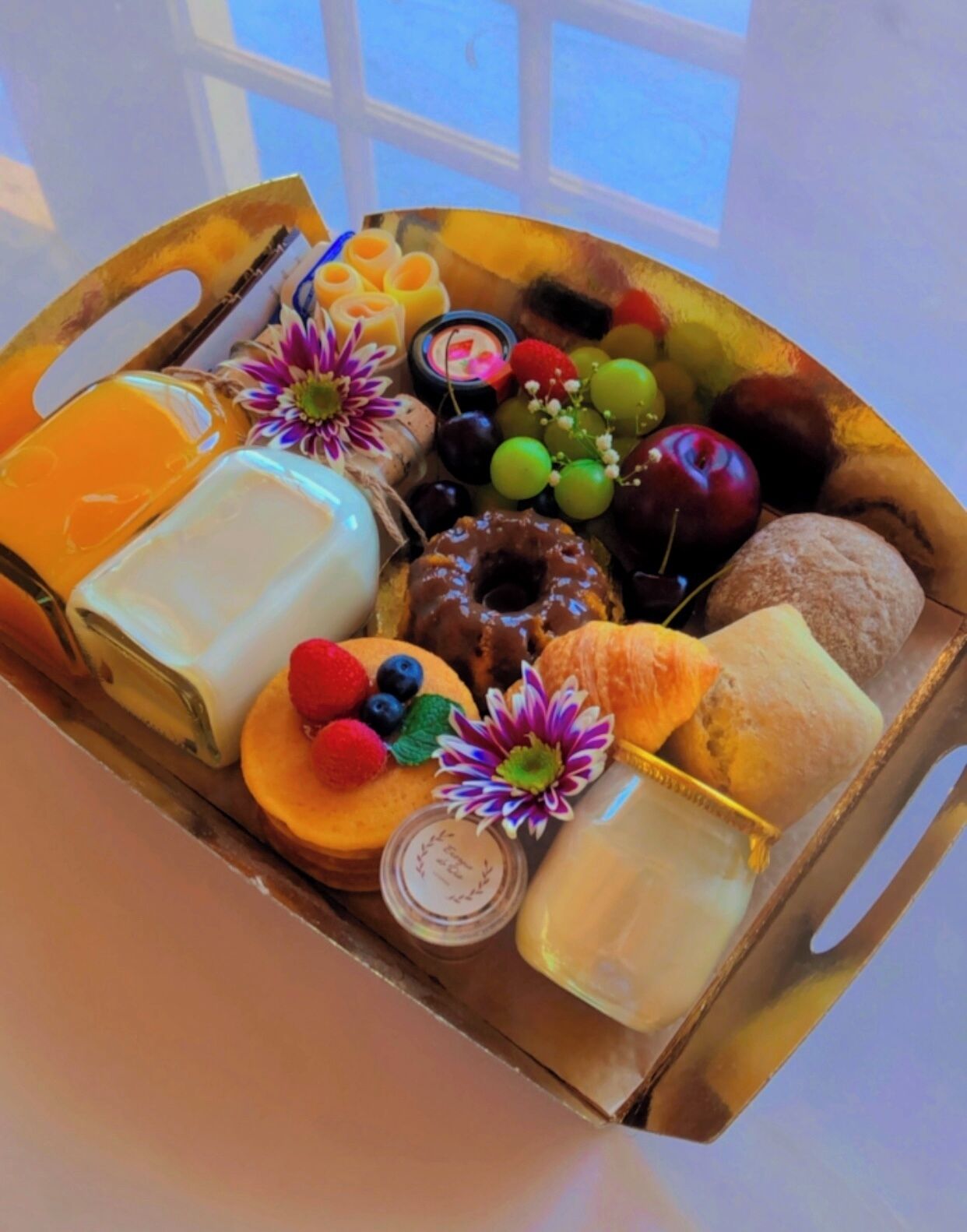 Een dienblad met diverse lekkernijen, zoals fruit, gebak en een kaars.