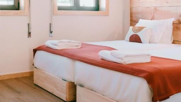A bedroom with two beds, wooden headboard, and a window with a view of buildings. - Campanha Apartment by Porto Stories (Porto)