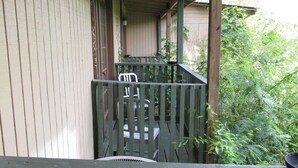 A wooden porch with a white chair, an air conditioning unit, and a view of greenery. - Charming hotel in Mayo with AC, WiFi, fitness room (Mayo)