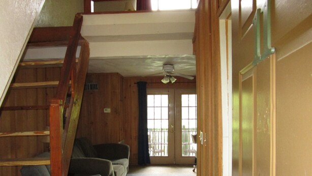 A staircase leading to a second floor, a door with a window, and a ceiling fan in a room with wooden walls and carpeted floor. - Charming hotel in Mayo with AC, WiFi, fitness room (Mayo)