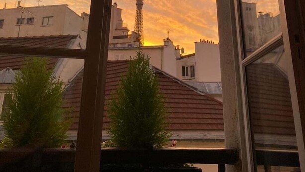 Vista a través de una ventana con un atardecer y una torre en la distancia.