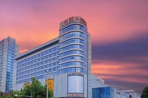 Un hotel de varios pisos con fachada curva, amplias ventanas y un letrero llamativo en la parte superior.