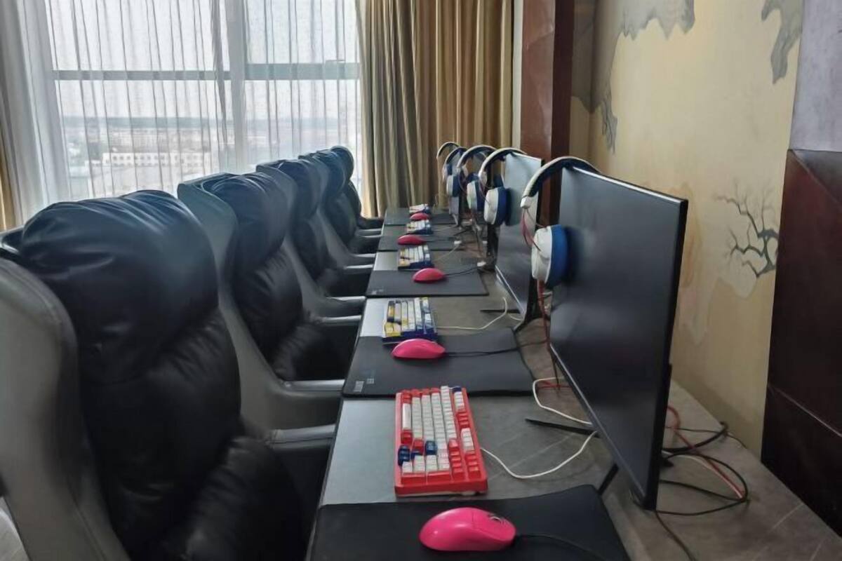 A conference room with rows of black leather chairs, individual computer stations with monitors, keyboards, and mice.