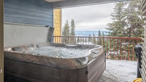 Boblebad på en balkon med udsigt til træer og bjerge.