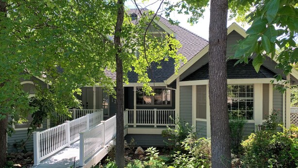 A house with a porch, a white fence, and a garden.