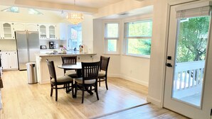 A modern kitchen with white cabinets, a stainless steel refrigerator, and a dining area with a round table and four chairs.