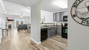 A modern kitchen with grey cabinets, a black stove, and a welcome sign with an eagle emblem. - Eagles Landing 1BR Heaven (Pigeon Forge)