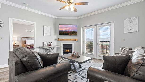 A living room with leather sofas, a fireplace, a ceiling fan, and a TV mounted above it. - Eagles Landing 1BR Heaven (Pigeon Forge)