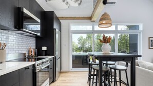 Une cuisine moderne dotée d’une grande cuisinière, de meubles noirs et d’un coin repas avec des tabourets.