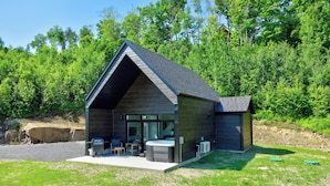 Une cabane moderne dotée d’un toit en pente, d’un patio avec coin salon extérieur et d’un jacuzzi.