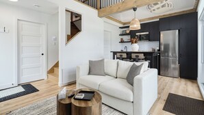 Un salon moderne avec un canapé, une table basse et un escalier menant à une mezzanine.