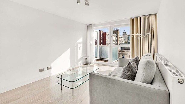 A modern living room with a glass coffee table, a grey sofa, and a view of a cityscape through large windows. - City Relay Radiant Chelsea Flat with City View (London)