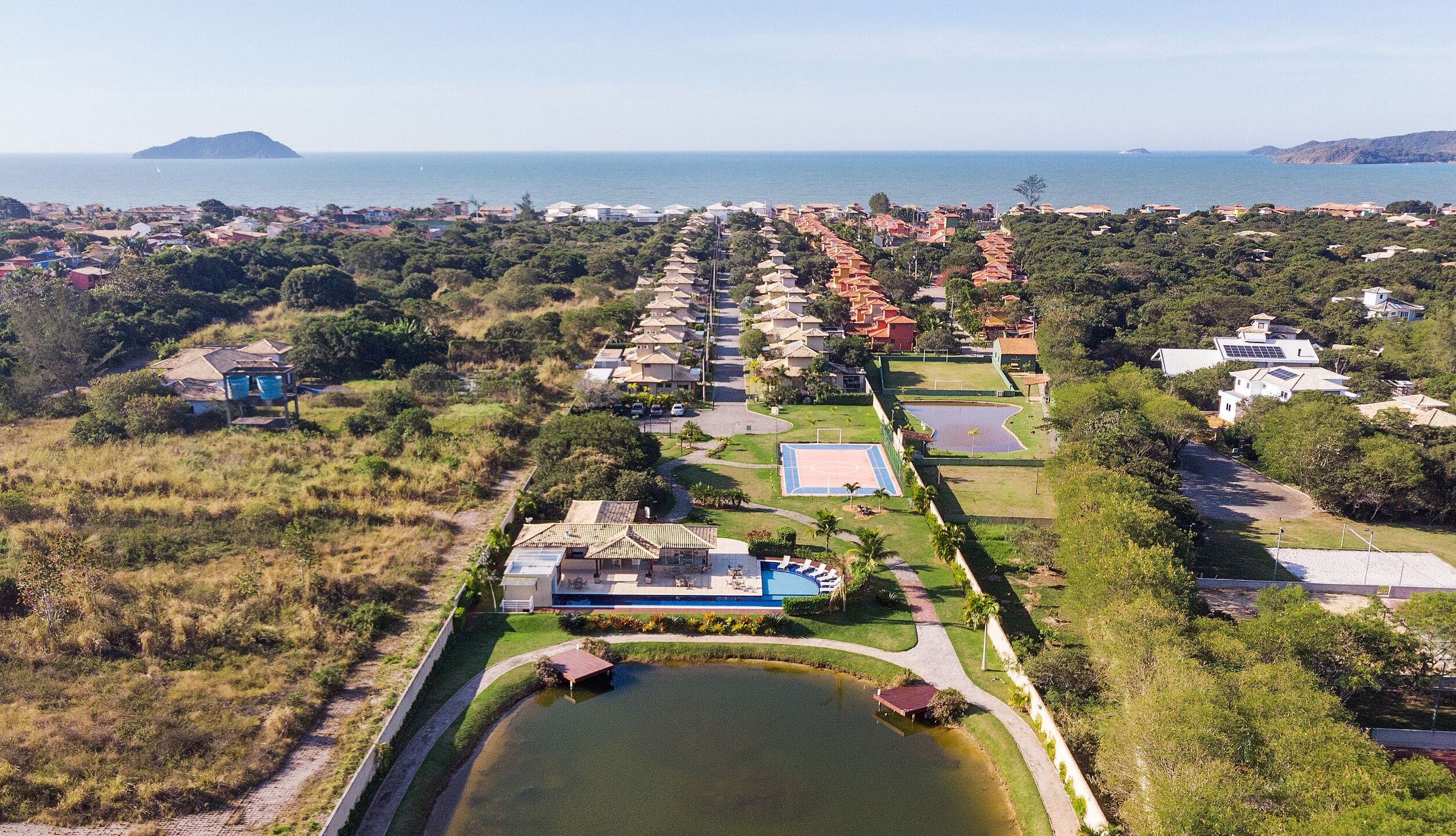 A residential area with houses, a swimming pool, and a view of the sea.
