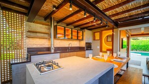 A modern kitchen with a central island, built-in appliances, and a view of a swimming pool. - Bz01 Casa Piscina Priv 150m Da Praia  (Buzios)