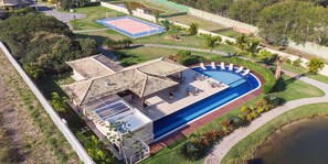 Eine Vogelperspektive eines Resorts mit einem Schwimmbad, einem Tennisplatz und einem überdachten Patio.