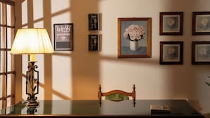 A dining area with a table, chairs, a lamp, and framed artwork on the wall.