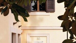 A building entrance with a door, a window with shutters, and a gravel pathway.