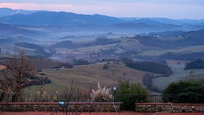 A rural landscape with rolling hills, a stone wall, and a distant mountain range.