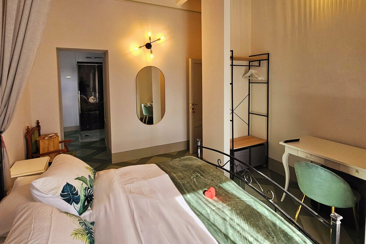 Een slaapkamer met een bed, een bureau, een spiegel en een deur naar een andere kamer.