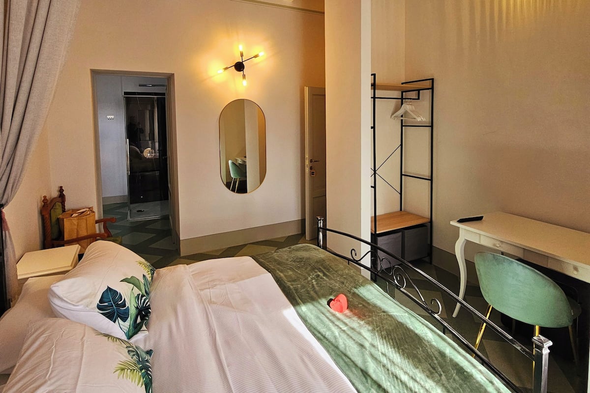 Une chambre à coucher comprenant un lit, un bureau, un miroir et une porte donnant sur une autre pièce.