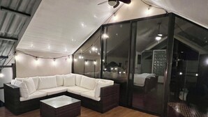 A modern loft-style room with a sectional sofa, a glass sliding door, and a wooden floor. - Charming 2-bedroom Lake View House in Puerto San Luis with WiFi (puerto san luis)