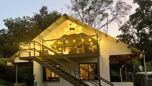A two-story house with a balcony, a staircase, and string lights. - Charming 2-bedroom Lake View House in Puerto San Luis with WiFi (puerto san luis)