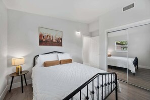 Une chambre à coucher avec un lit, une table de chevet, une lampe et un tableau au mur.