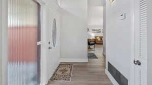 En hall med en mönstrad matta, en dörr med en dekorativ glaspanel och en lampa på väggen.