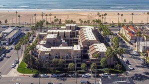 Un hôtel en bord de mer doté d’une cour intérieure, entouré de palmiers et offrant une vue sur la plage.